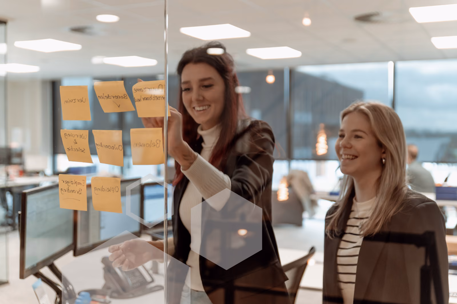 Twee vrouwen lachend tijdens een brainstormsessie bij Solid Systems.