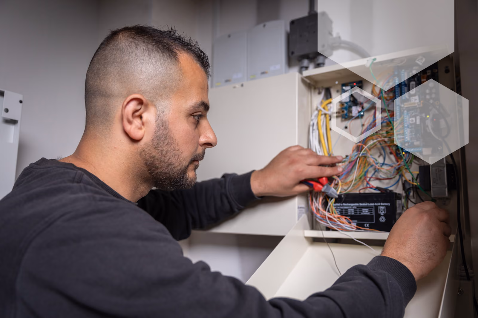 Een elektromonteur van Solid Systems bevestigd de juiste bedrading in een wandkast. 