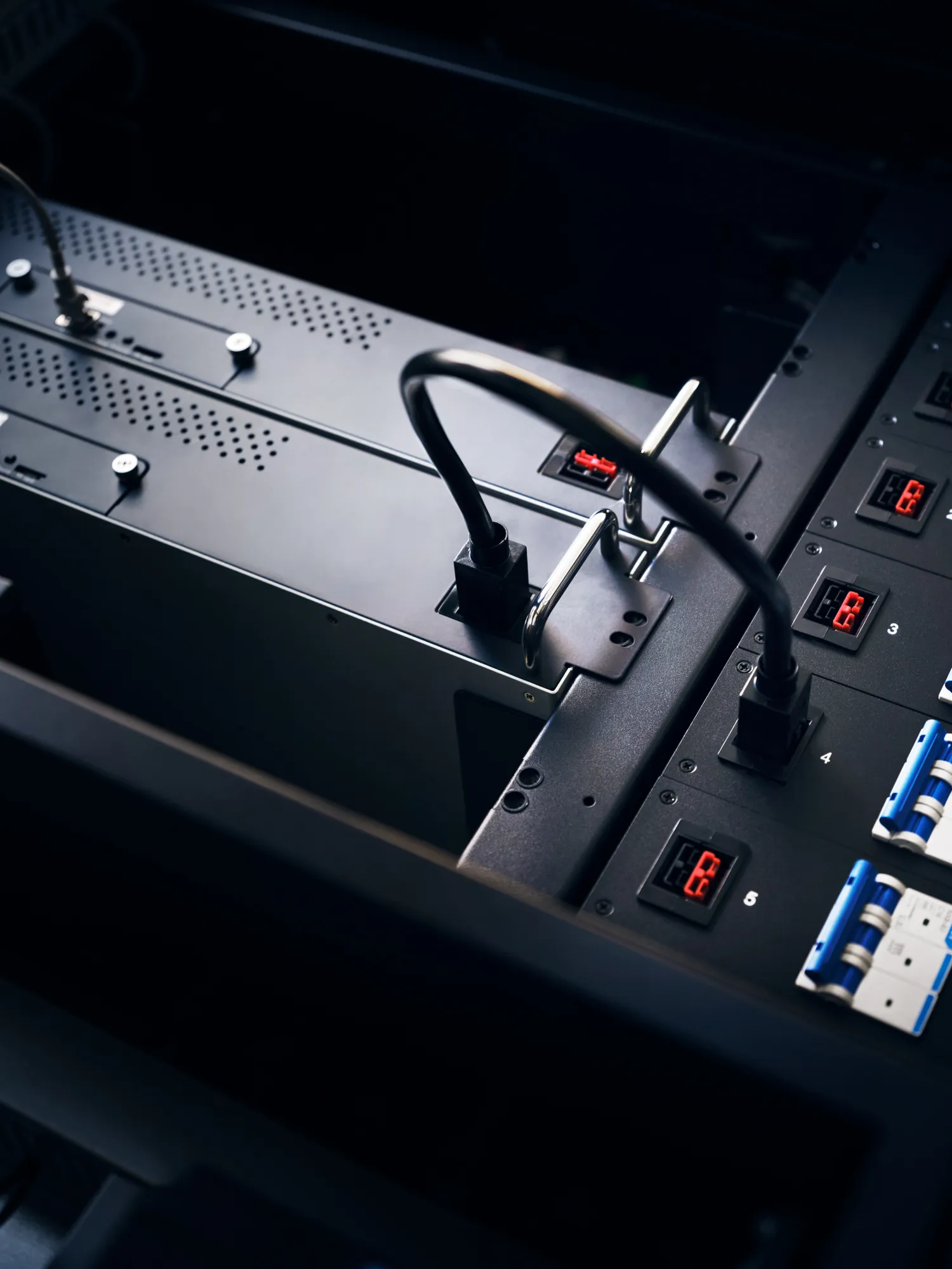 Close-up of electronic equipment with cables plugged into power management units displaying red digital readouts.