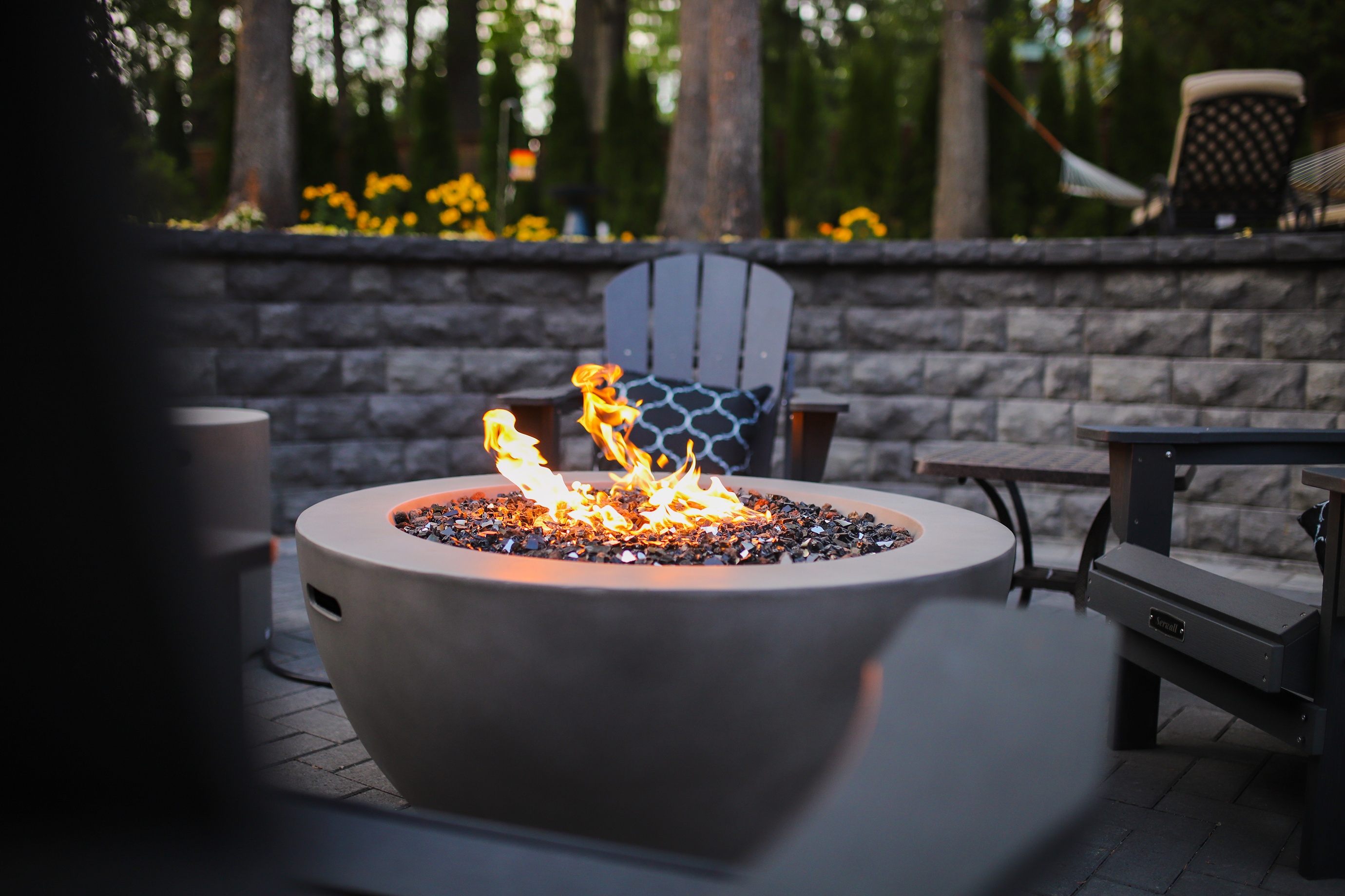 A fire pit with a hardscaped patio in the background