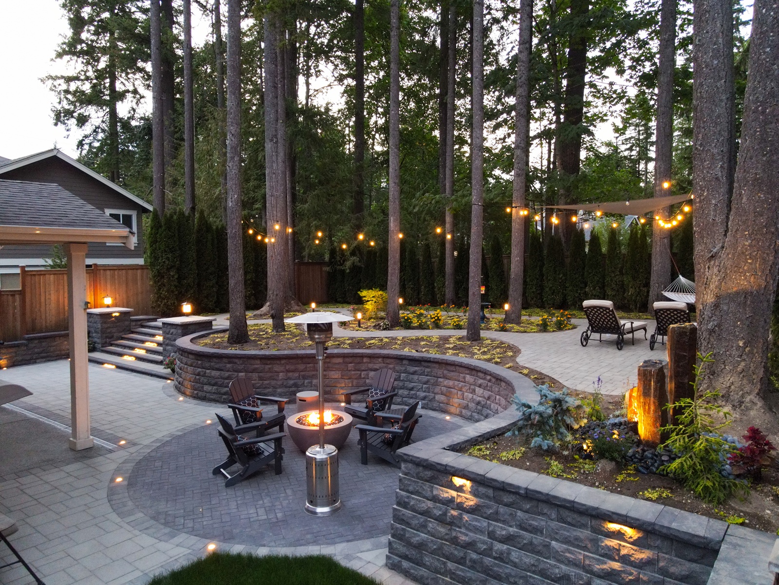 A backyard that underwent landscaping services with fire pit and customized hardscape design