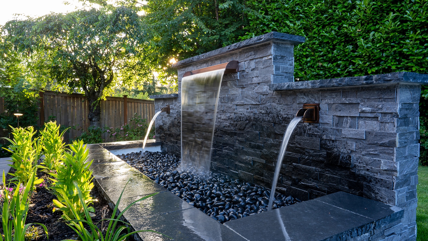 A waterfall fountain beside a plantbox, installed for added backyard elegance