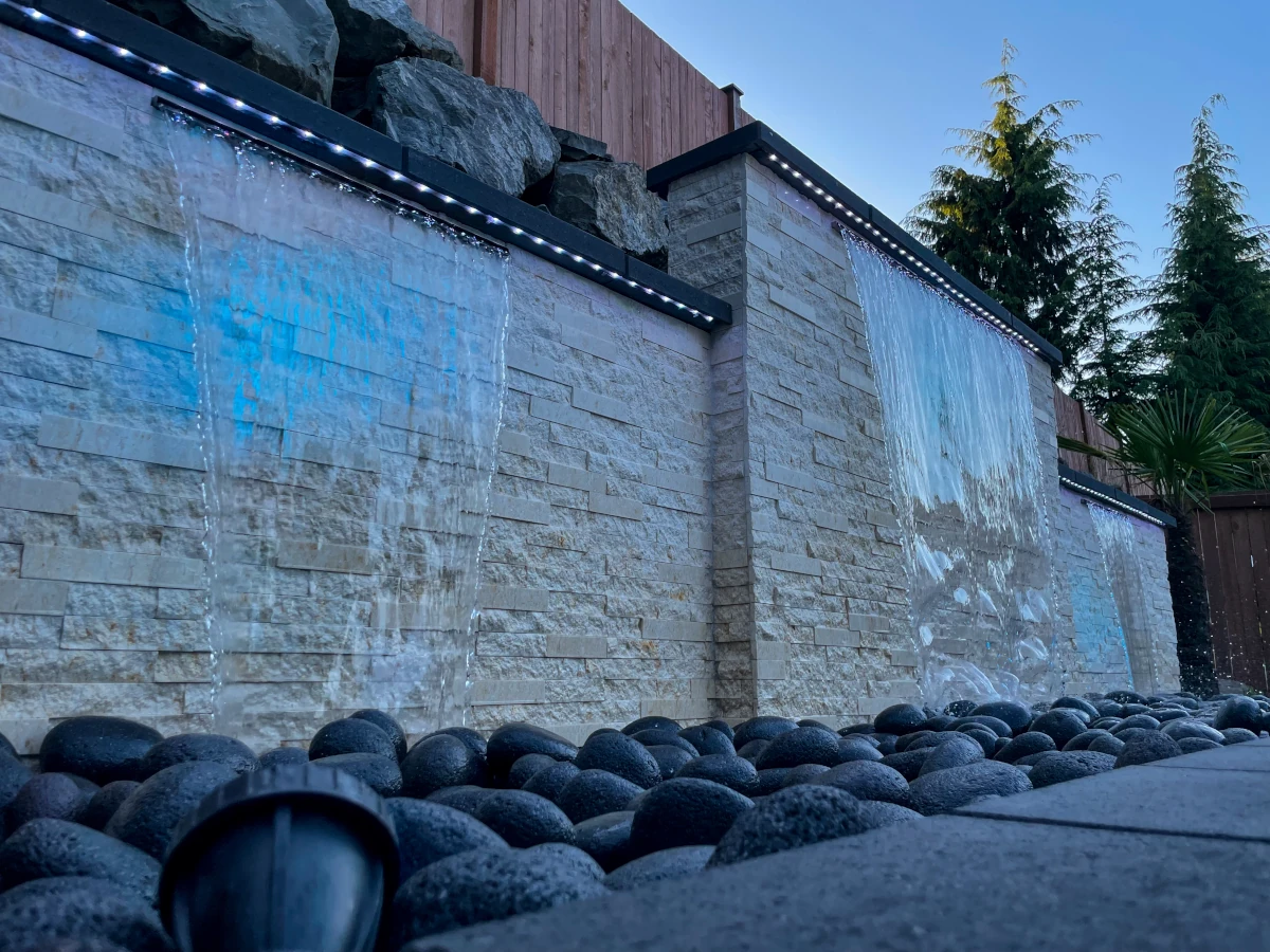 Custom outdoor water wall feature with LED lighting and stacked stone design by Angkorscape, Greater Seattle landscape contractor