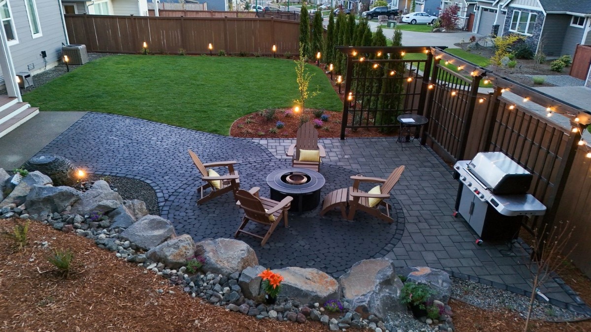 A fire pit surrounded by four wooden chairs near an outdoor grill
