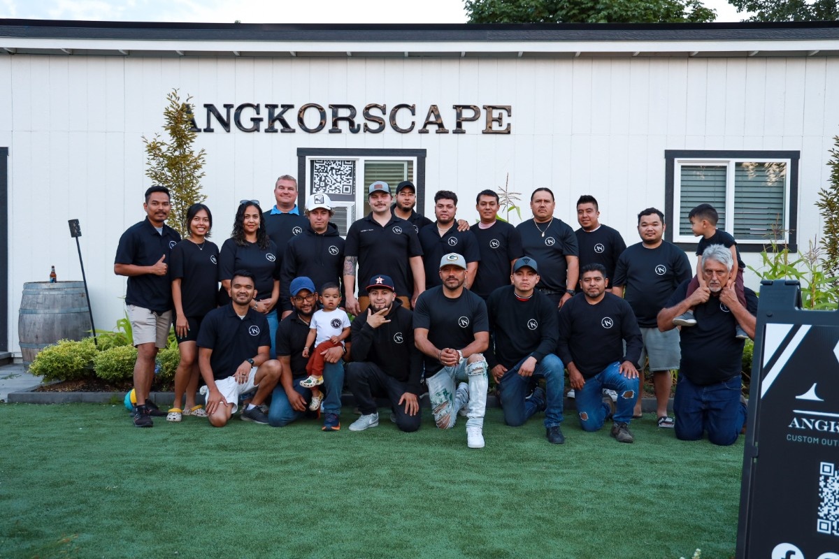 Group of people wearing black shirts posing in front of a white building with Angkorscape sign.