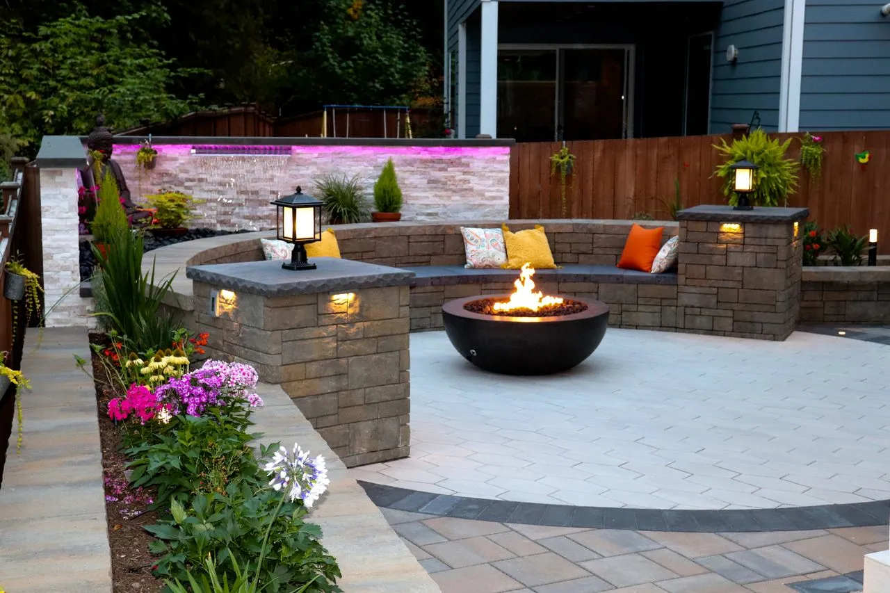 Newly remodeled backyard with custom hardscaping, water feature, and fire pit 