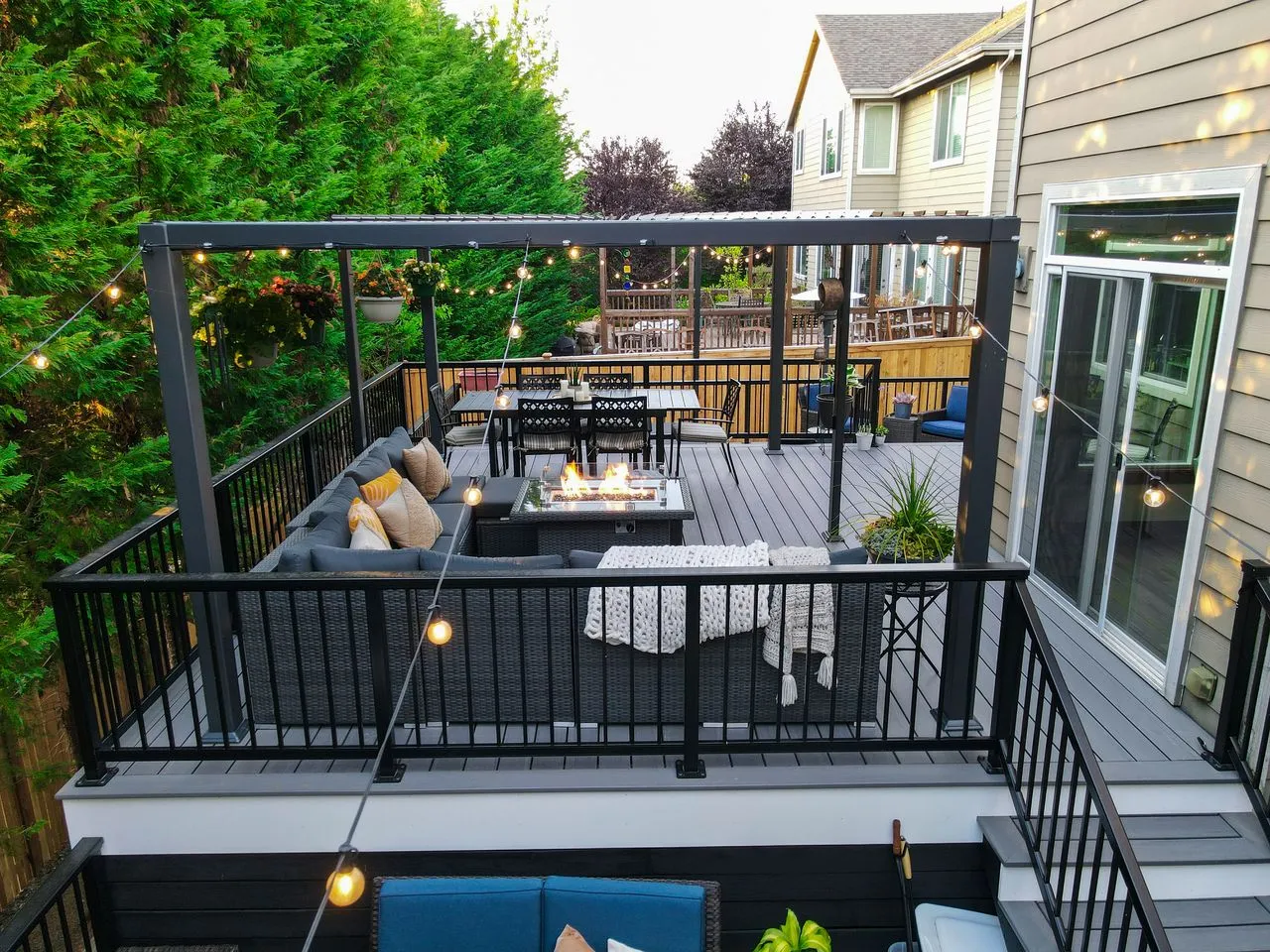 A wooden deck patio with dining table and sofa set for entertaining guests 