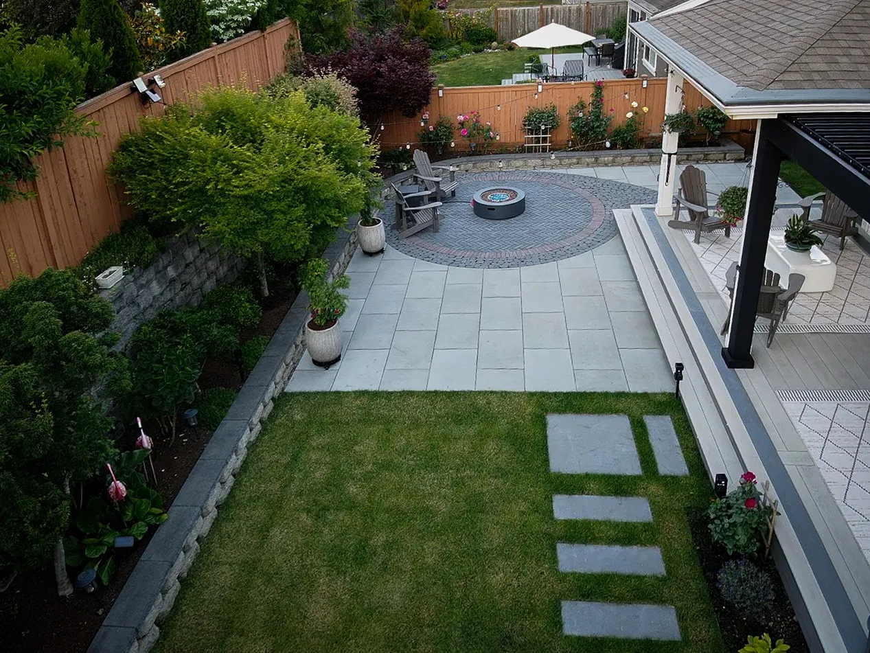 Aerial view of landscaped property with fire pit and custom pavement.