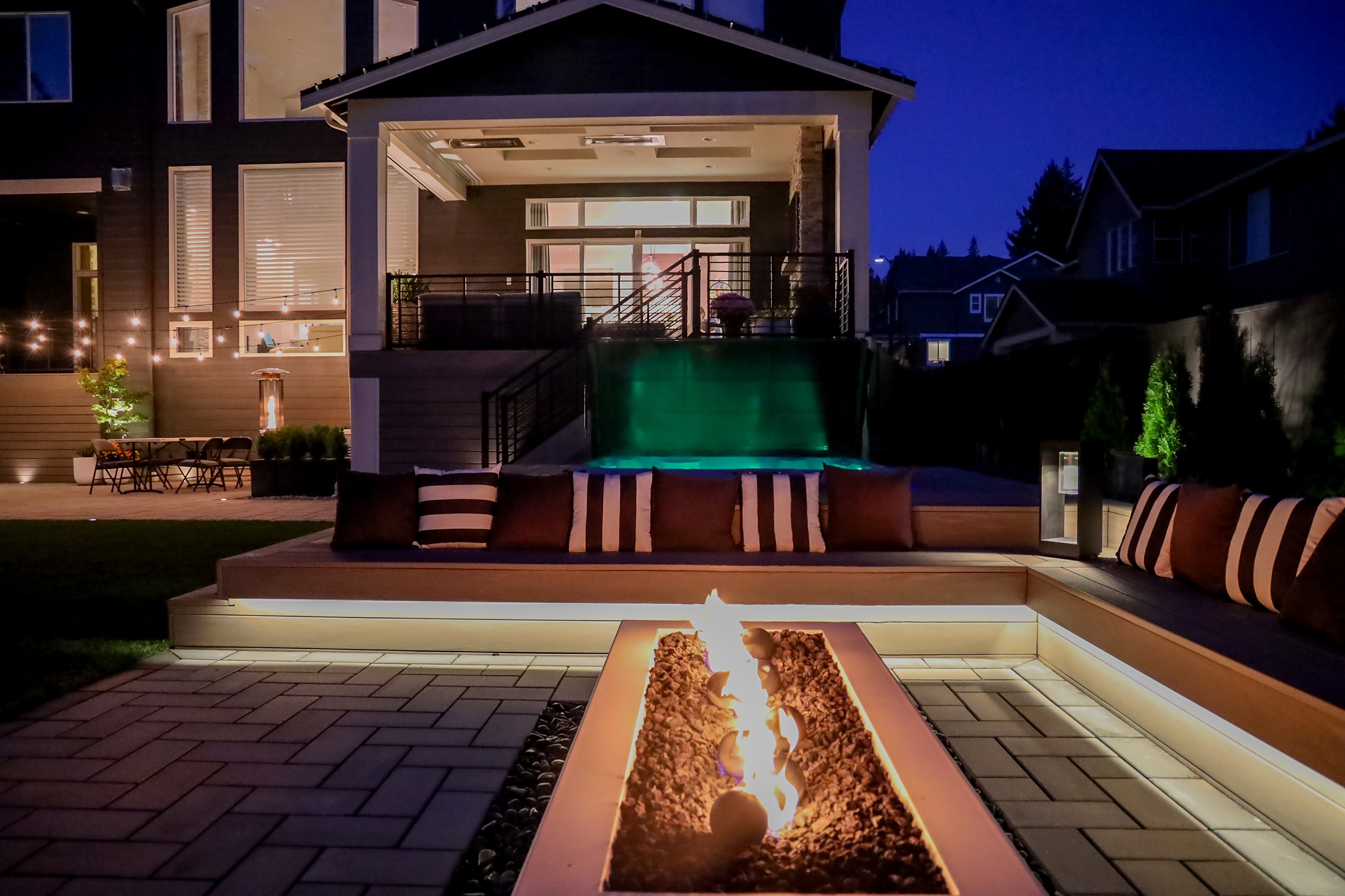 Newly remodeled backyard with fire pit and custom pavers at night in a Seattle property 