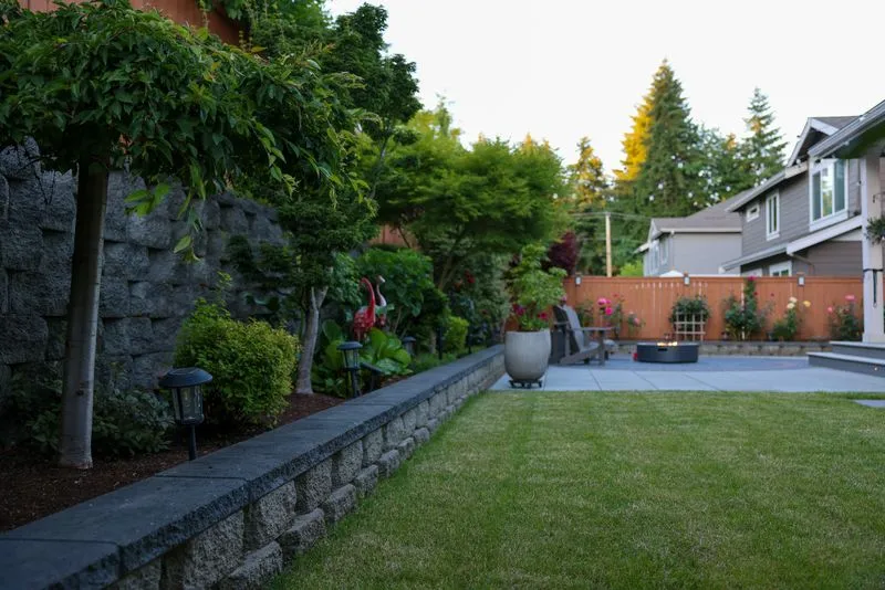 Aerial view of a multi-level backyard patio with sunken fire pit, hardtop gazebo, string lights, and manicured lawn at dusk