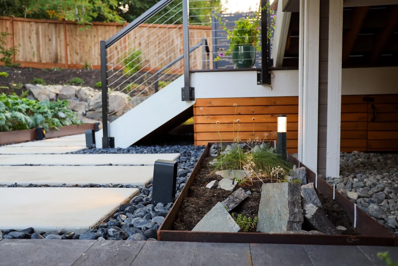 Stone steps with metal railing and gravel landscaping on a sloped Newcastle hillside property.