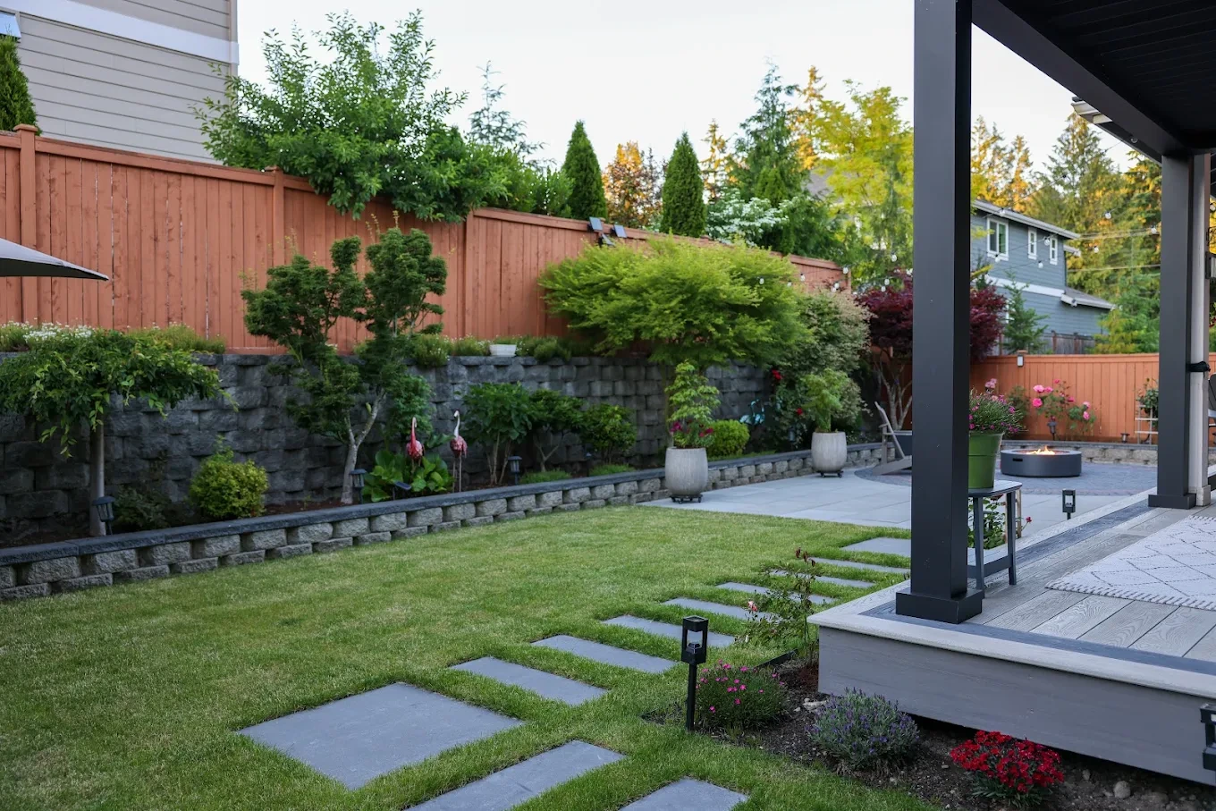 A Newcastle backyard with a covered patio, lawn, tiered garden beds, and a fire pit.