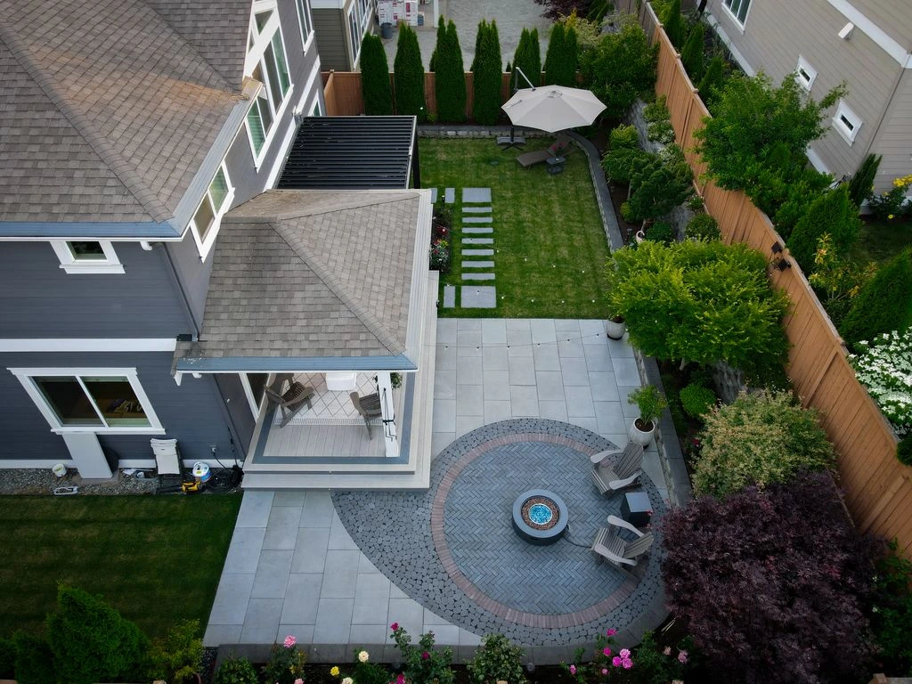 Aerial view of a Newcastle backyard after renovation, with a paver patio, fountain, and tiered plantings.