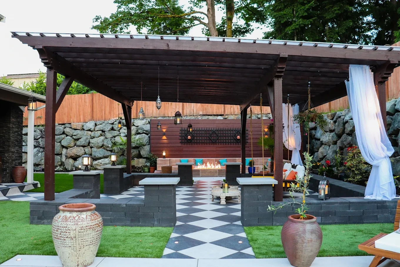 Issaquah outdoor pergola fire pit checkered patio stone walls lanterns
