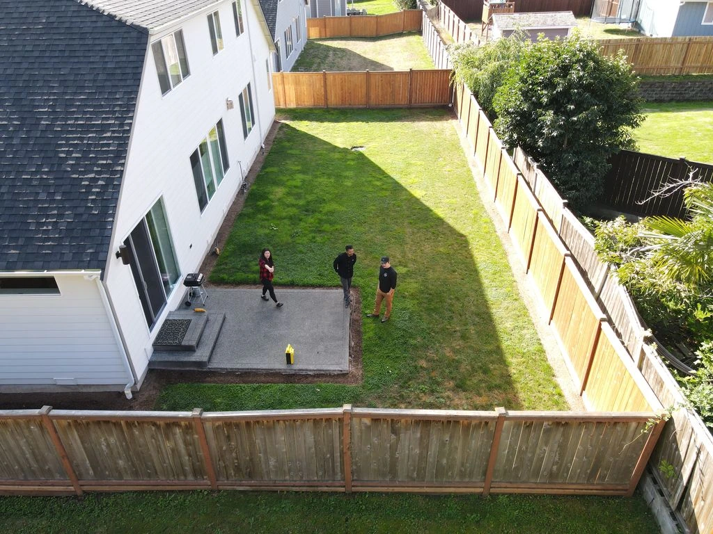 Aerial view of two workers inspecting a Snoqualmie backyard site with a wooden fence.