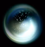 Abstract glowing circular light with small bright particles and a dark background.