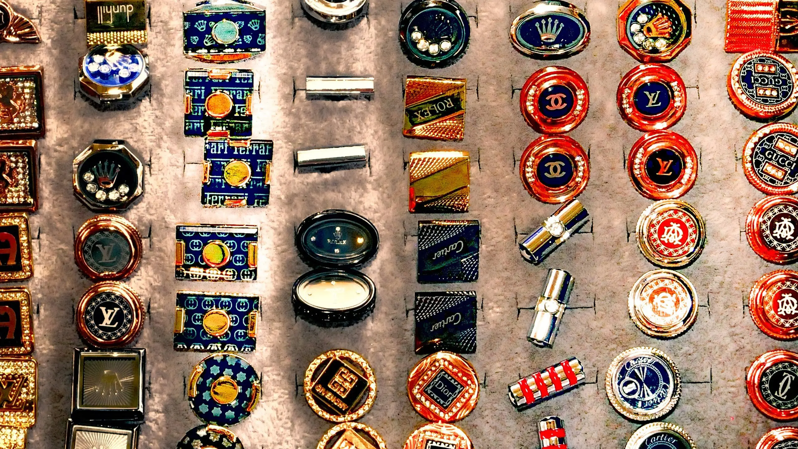 Merken zijn magie en daarom zijn er speldjes met merken zoals Chanel, Louis Vuitton, Gucci, Ferrari, Cartier en Rolex