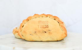Baked empanada stamped with 'Hongos Queso' on a marble surface.