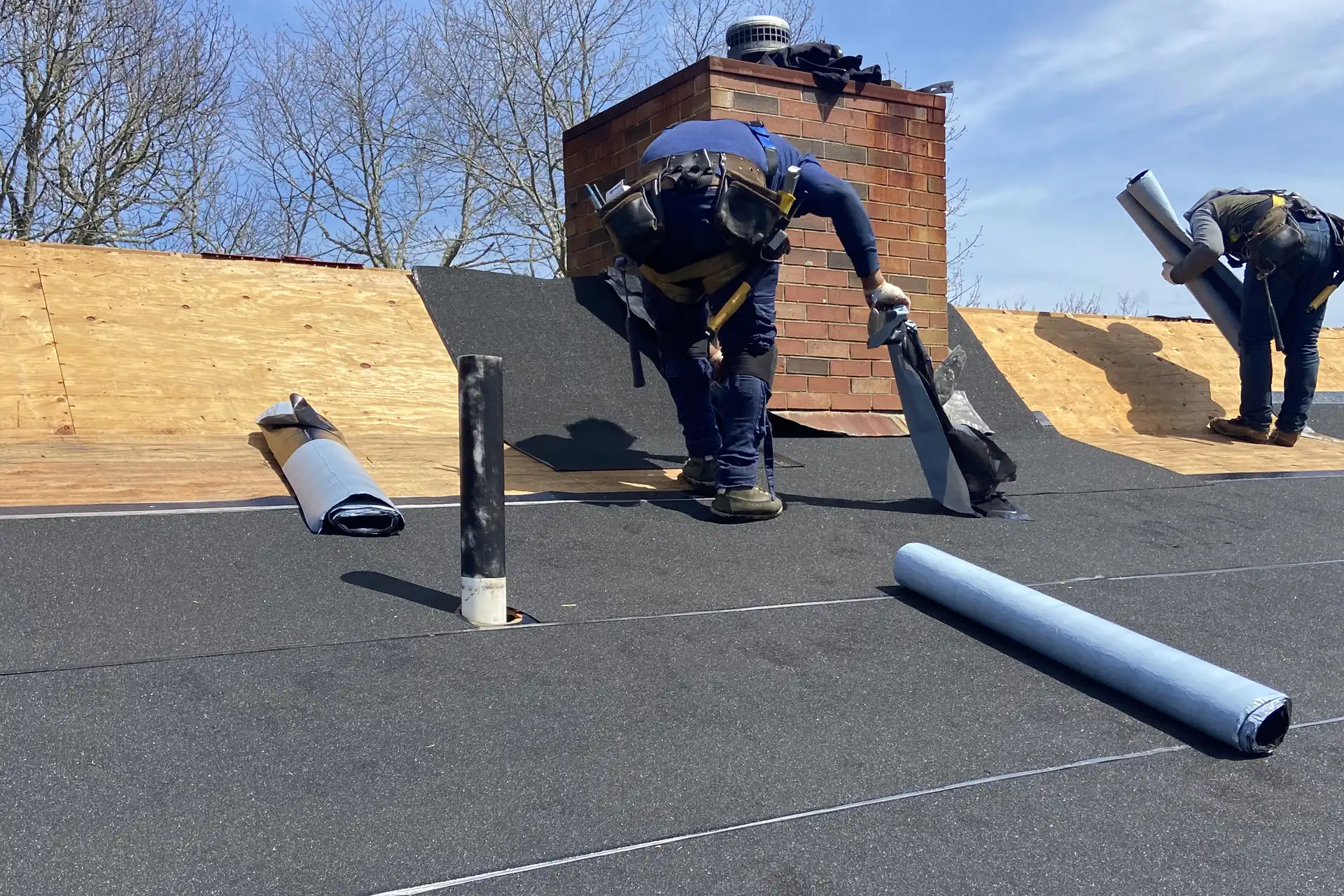 Roofing crew installing underlayment on a residential roof