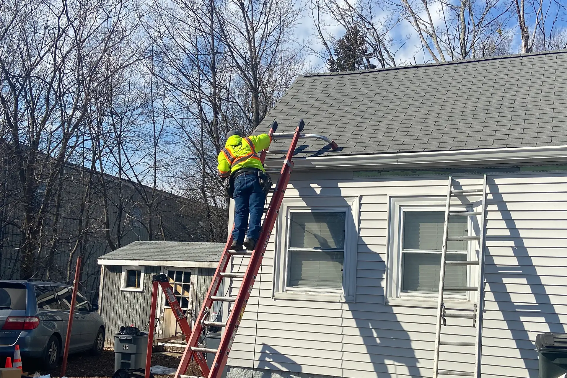 Contractor working on the roof of a gray-sided home