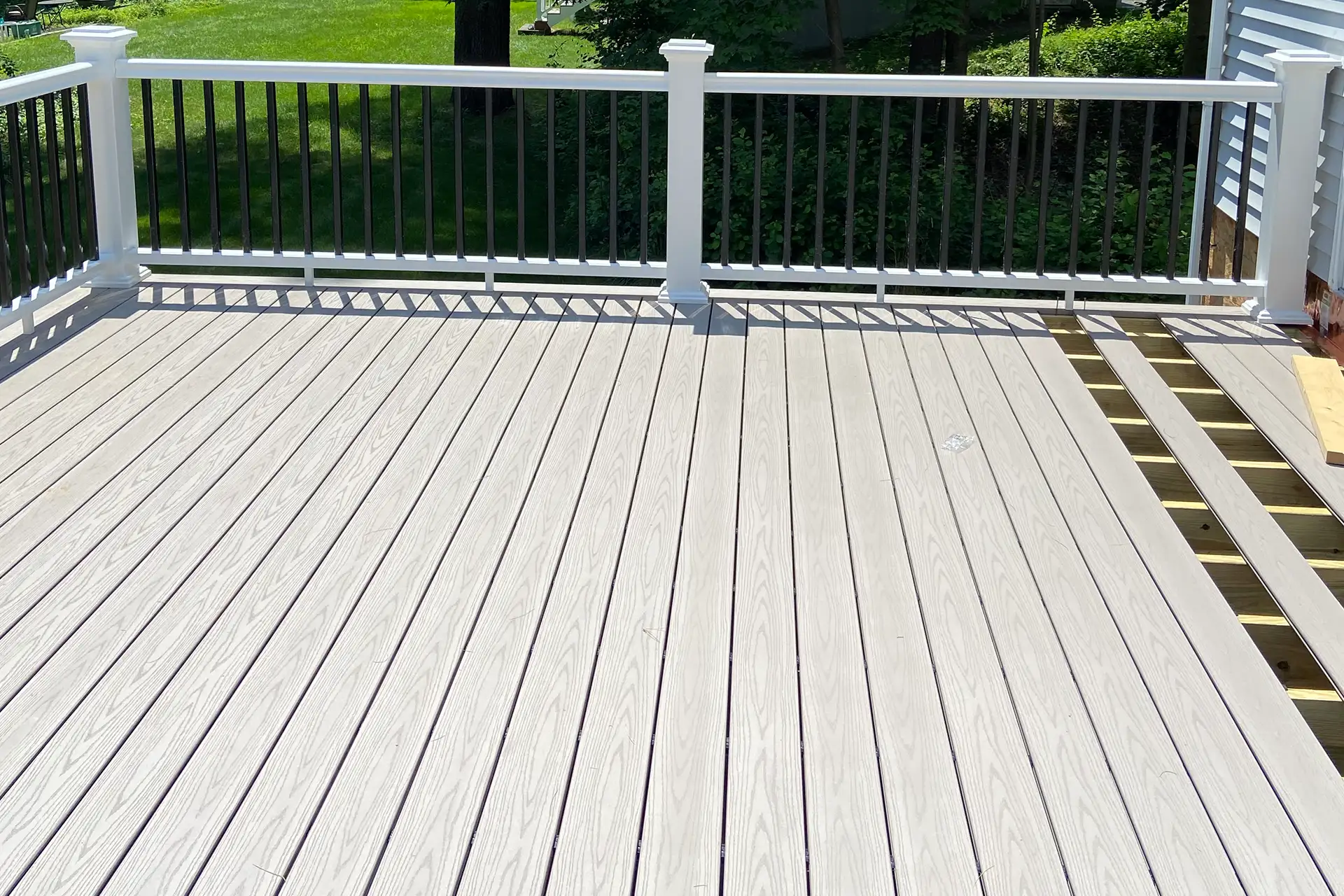 Composite deck with white railing overlooking a backyard