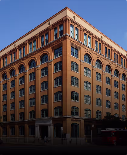 Large historic brick building with arched windows and decorative details under a clear blue sky.