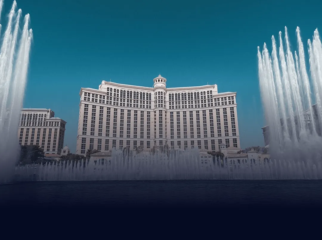 Bellagio hotel with its iconic fountain water jets shooting up against a blue sky.