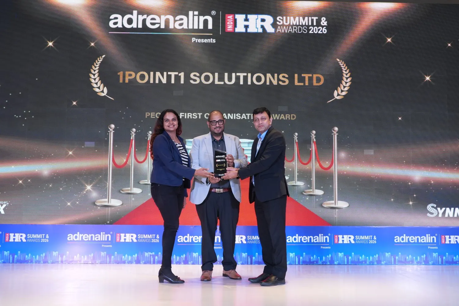 Three people holding an award in front of a backdrop reading 1POINT1 Solutions Ltd HR Summit Awards 2026.