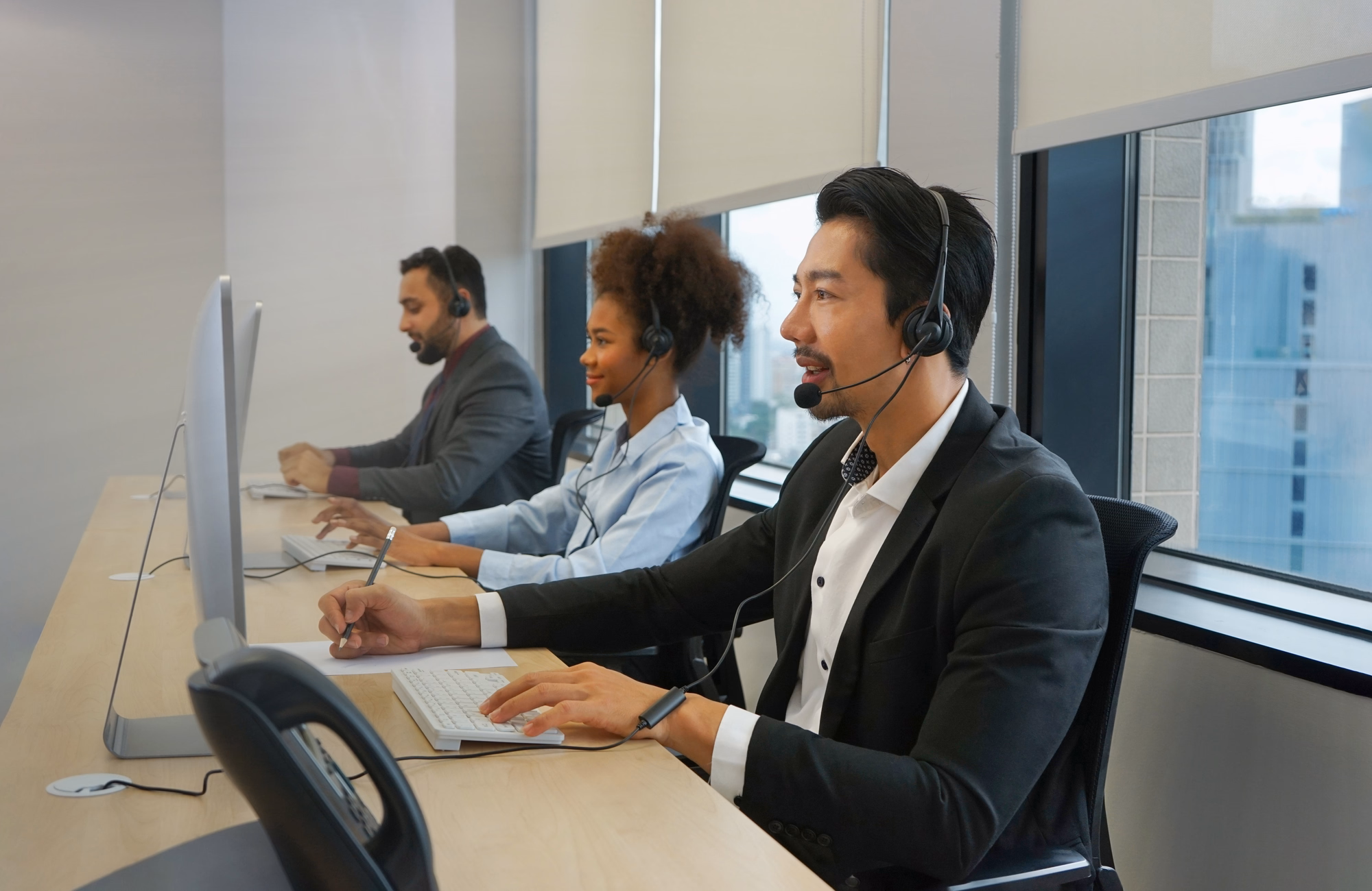 young technician man working in customer service agent at the call center office,counseling a customer and taking note, concept call center outsourcing business