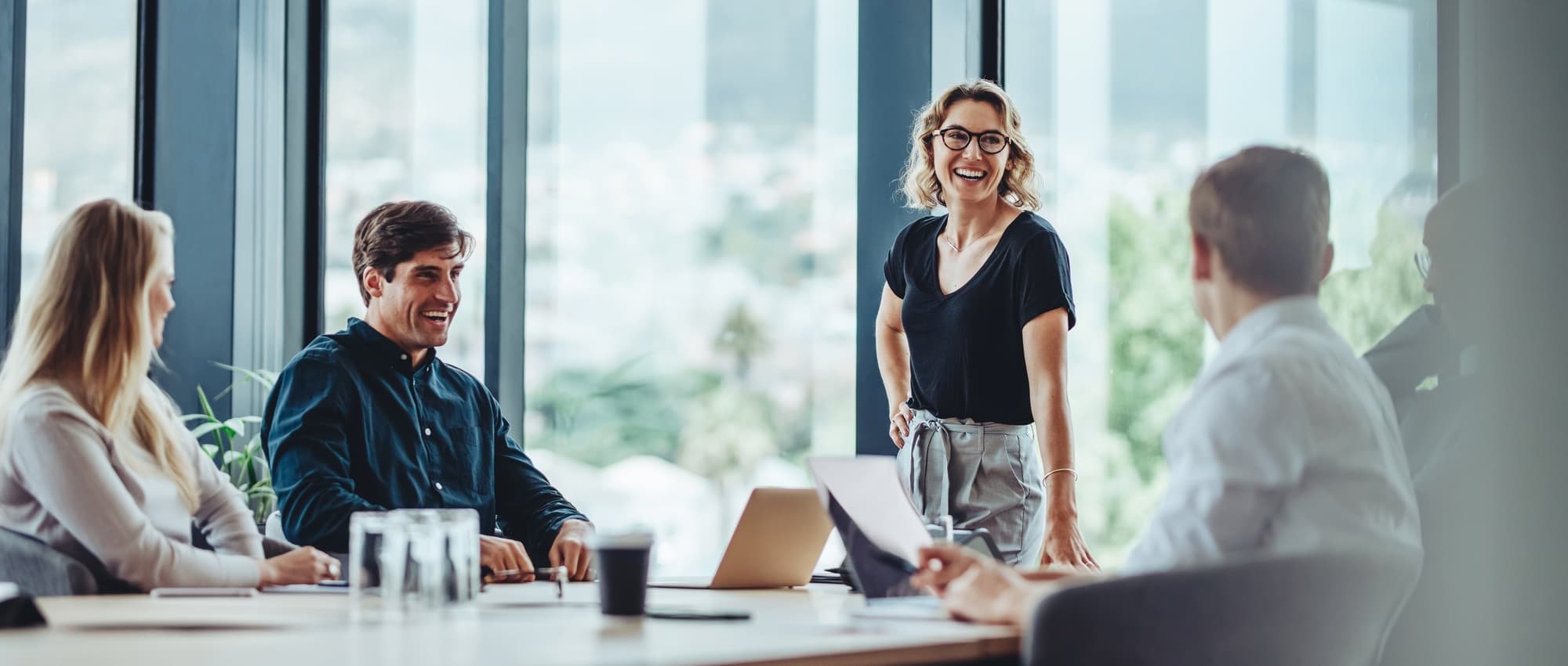 Group of colleagues engaging in a discussion during a business meeting in a conference room. Happy business people, men and women, collaborating and working towards their shared goals.
