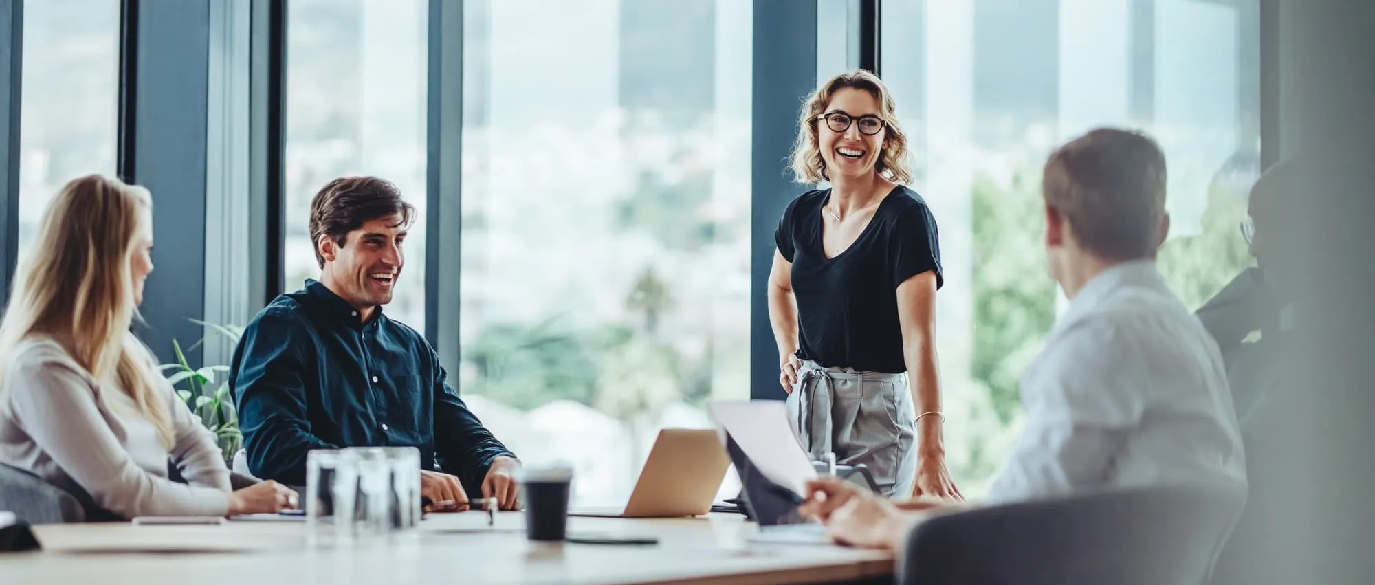 Group of colleagues engaging in a discussion during a business meeting in a conference room. Happy business people, men and women, collaborating and working towards their shared goals.