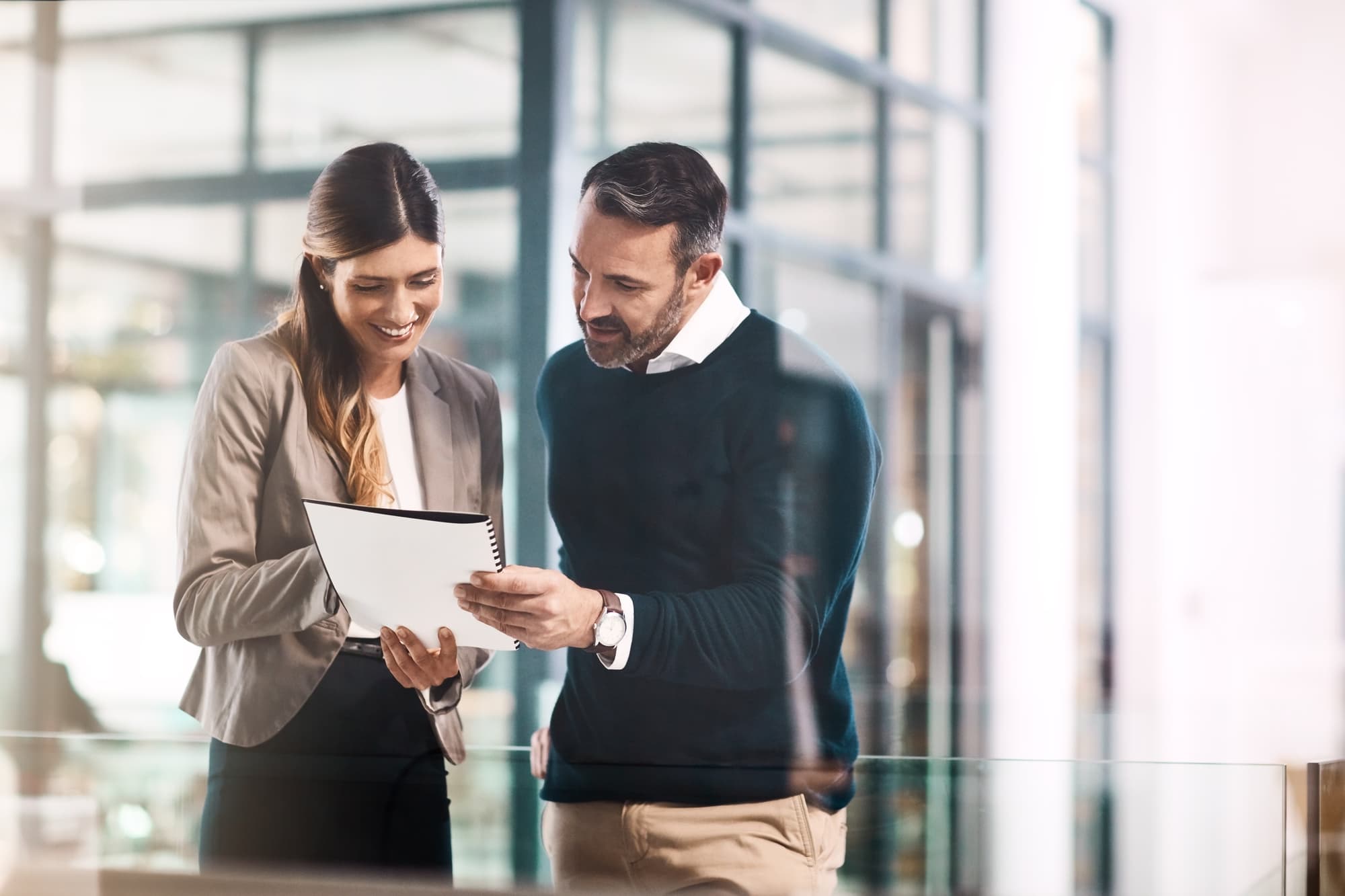 Man, woman and documents with reading in office for teamwork, advice or review for proposal. Business people, partner and attorney for feedback, compliance or conversation with paperwork in workplace