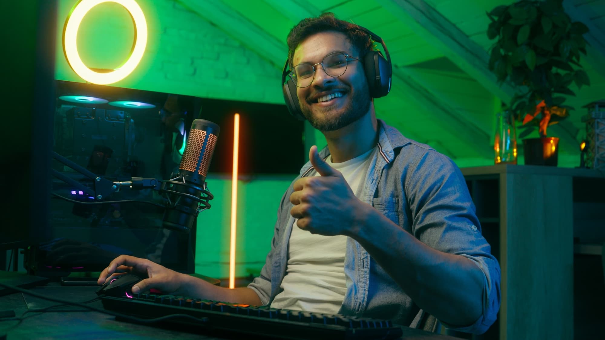 Night gaming neon video game addiction at home indoors Indian Caucasian man male guy in headphones playing internet online stream gamer streamer showing thumb up radio work typing smiling recommend