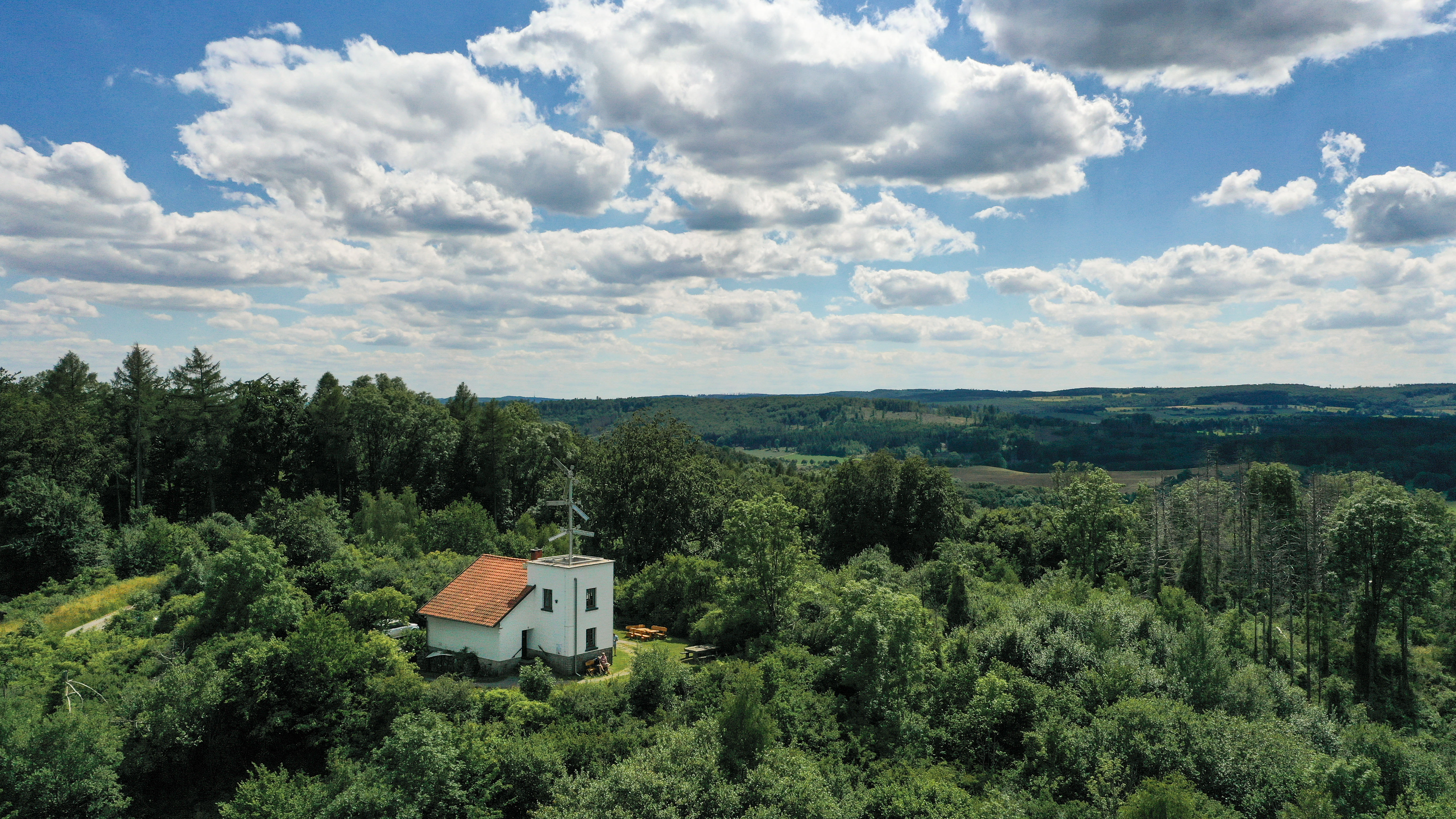 Telegrafenstation 32 umgeben von dichtem grünen Wald unter wolkigem Himmel.