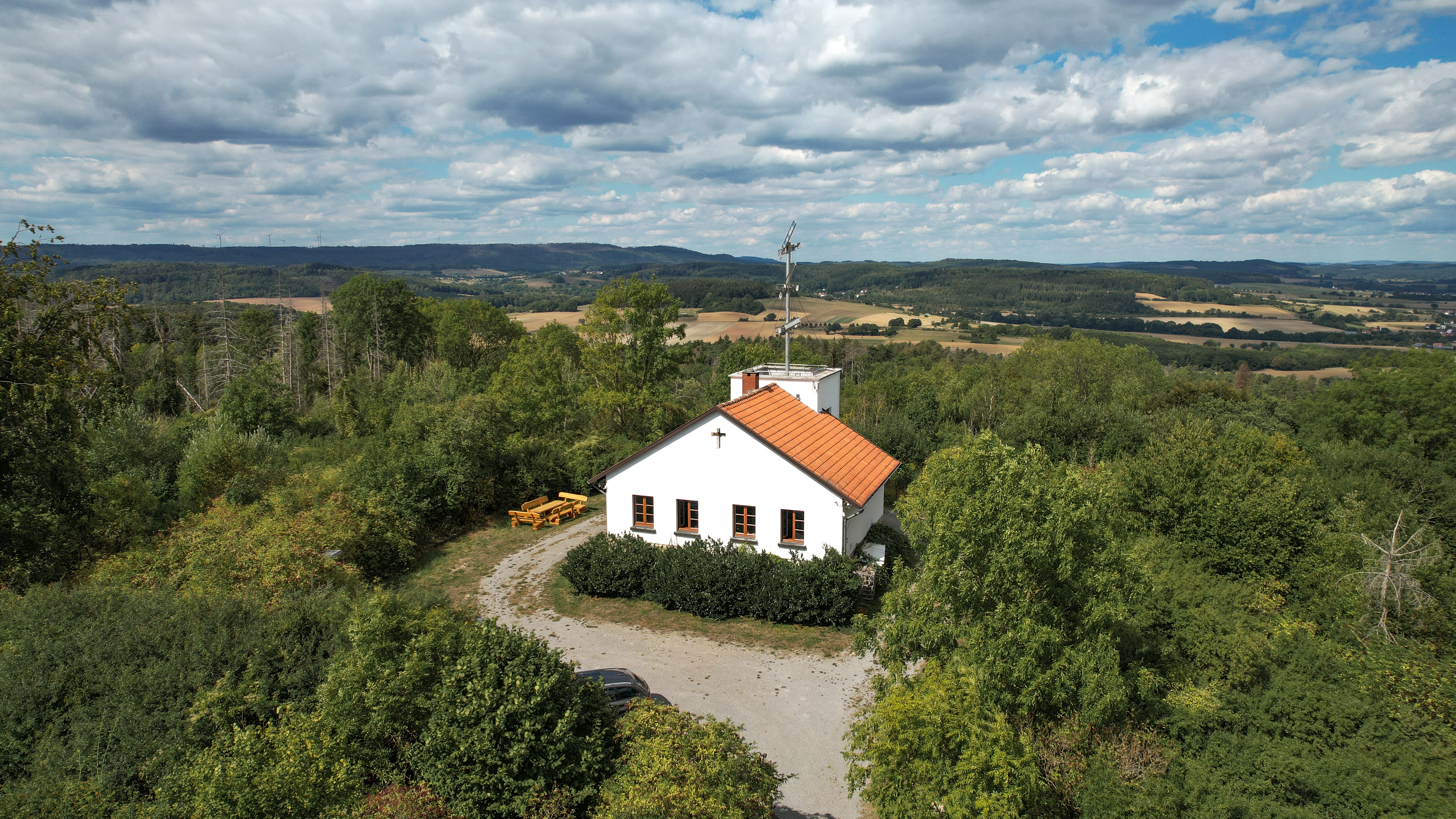 Telegrafenstation 32 umgeben von grünen Bäumen und Feldern unter bewölktem Himmel.