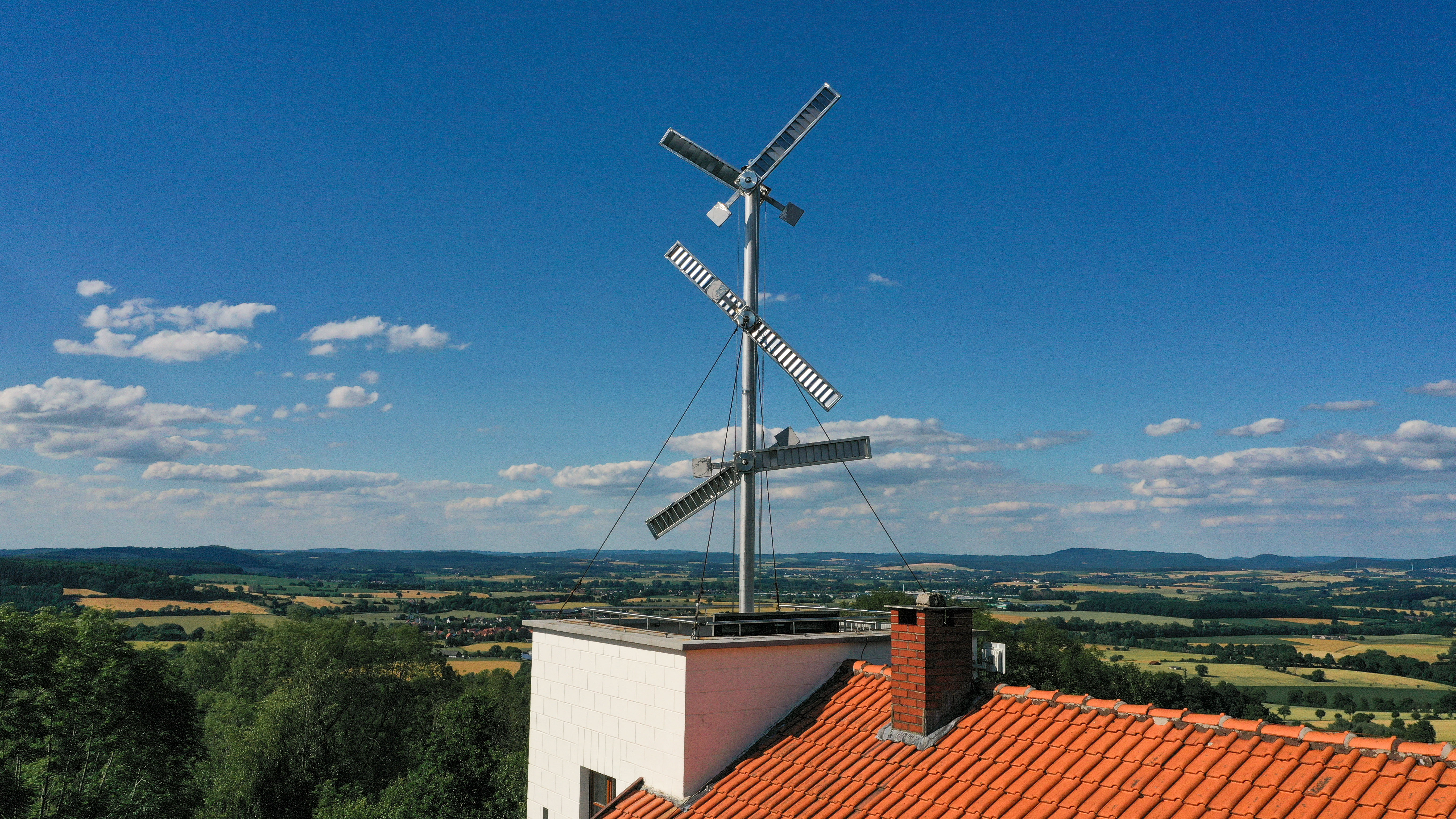 Die Telegrafen-Masten der Telegrafenstation 32, darunter grüne Felder und blauer Himmel mit vereinzelten Wolken.