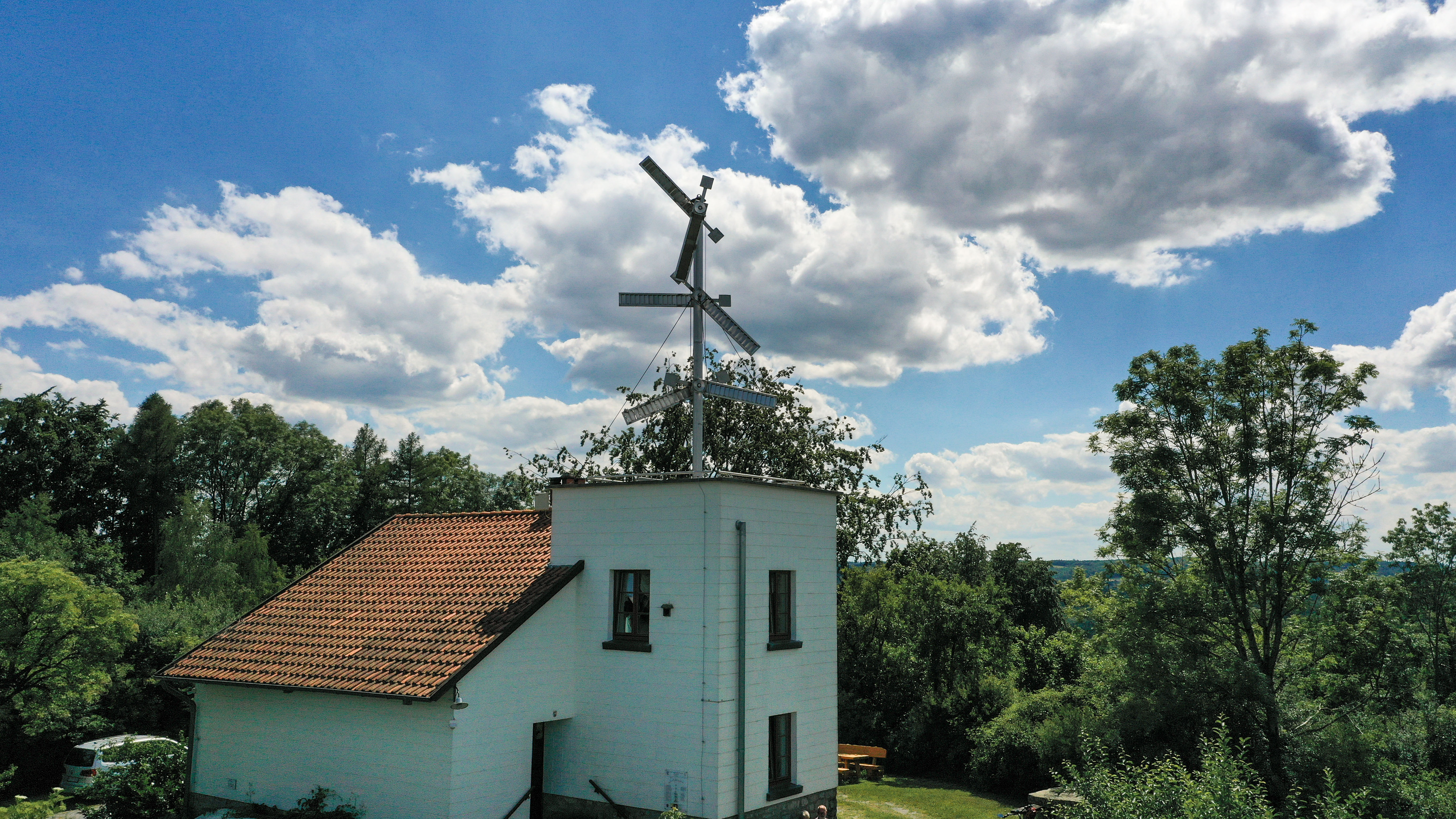 Telegrafenstation 32 umgeben von grünen Bäumen unter blauem Himmel mit Wolken.