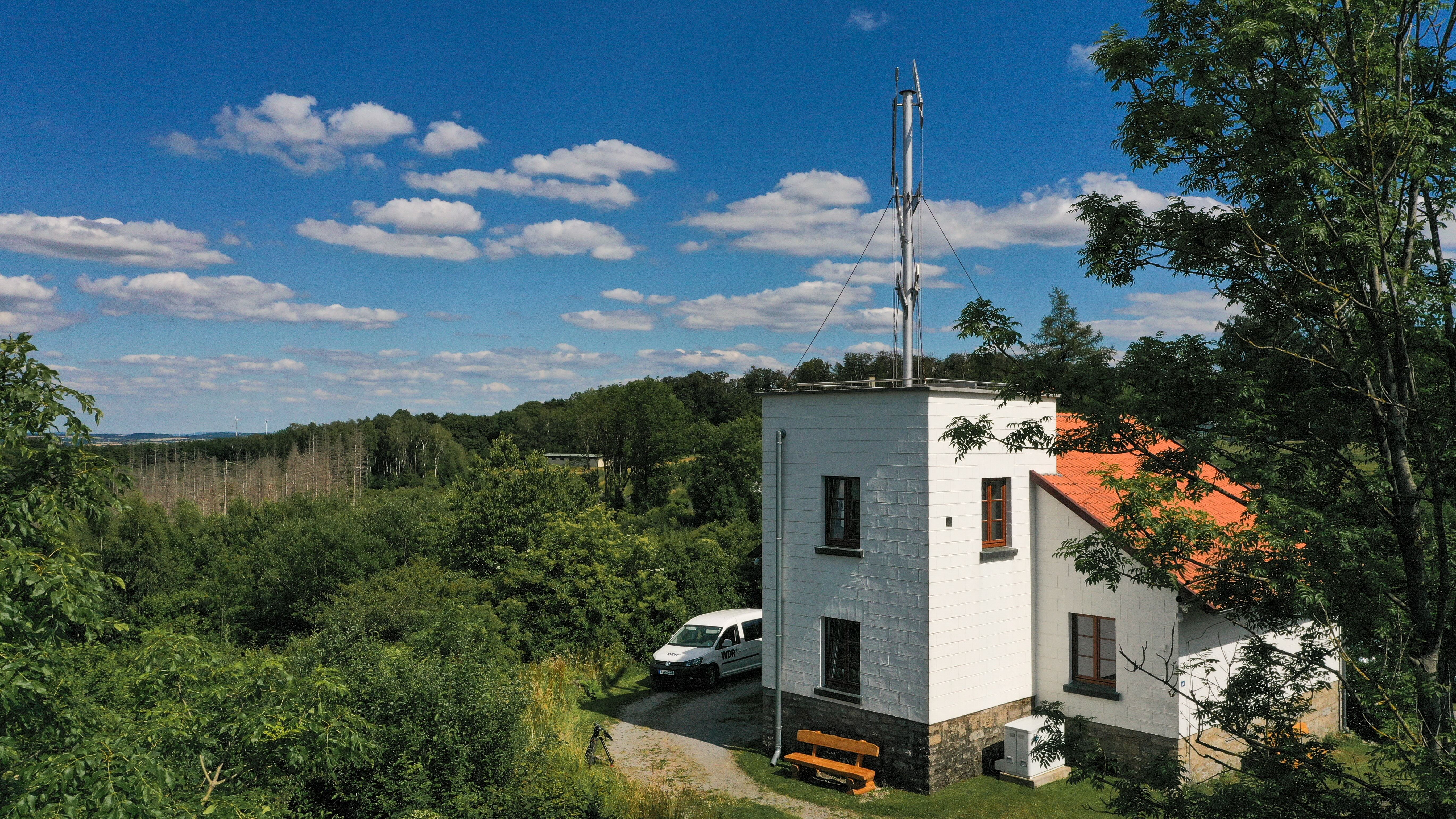 Telegrafenstation 32 umgeben von grünen Bäumen unter blauem Himmel mit weißen Wolken.