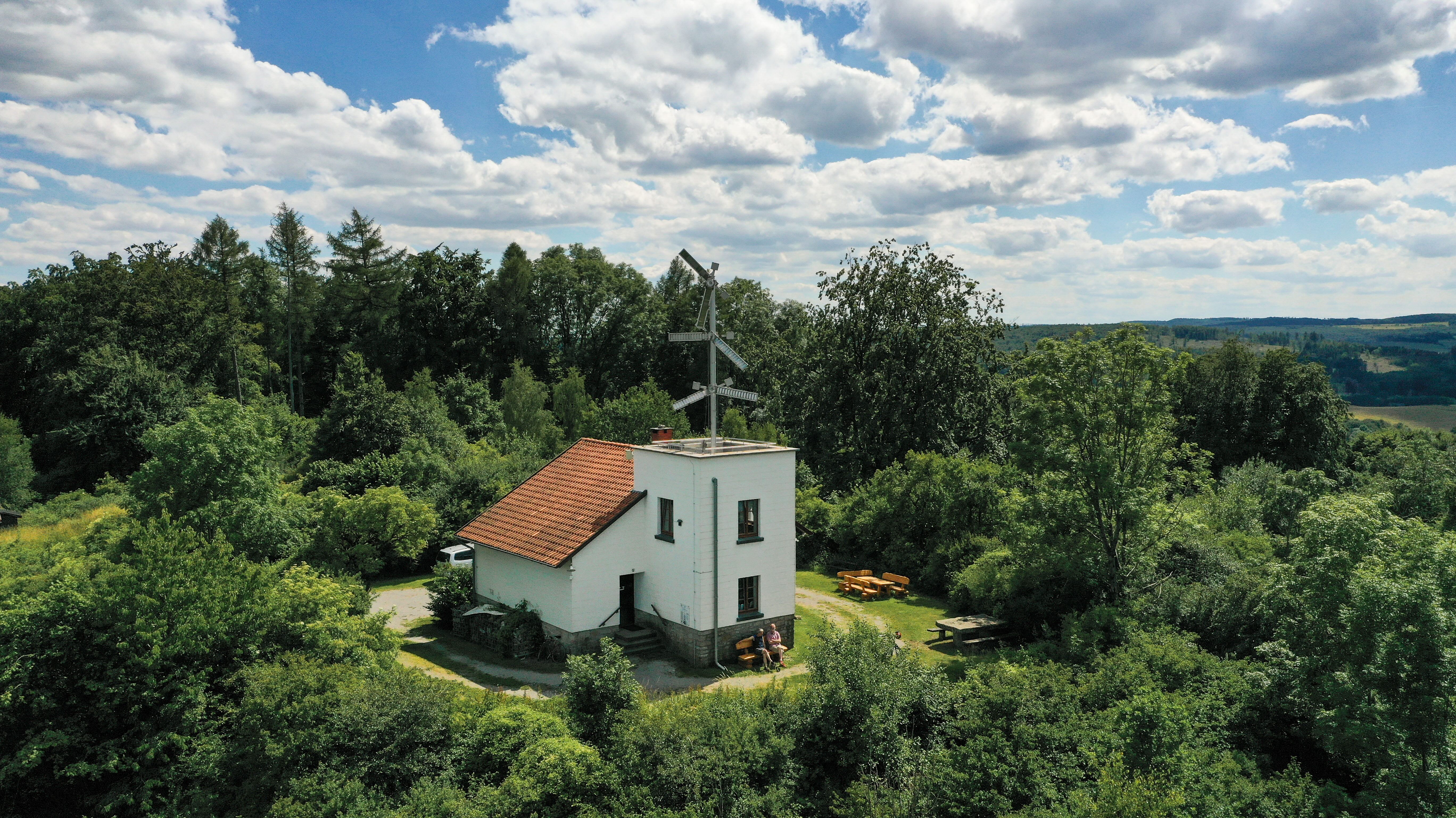 Telegrafenstation 32 umgeben von grünen Bäumen und Wiesen unter einem bewölkten Himmel.