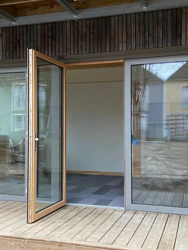 Porte de service vitrée avec ouvrant extérieur et menuiserie hybride sur façade moderne.