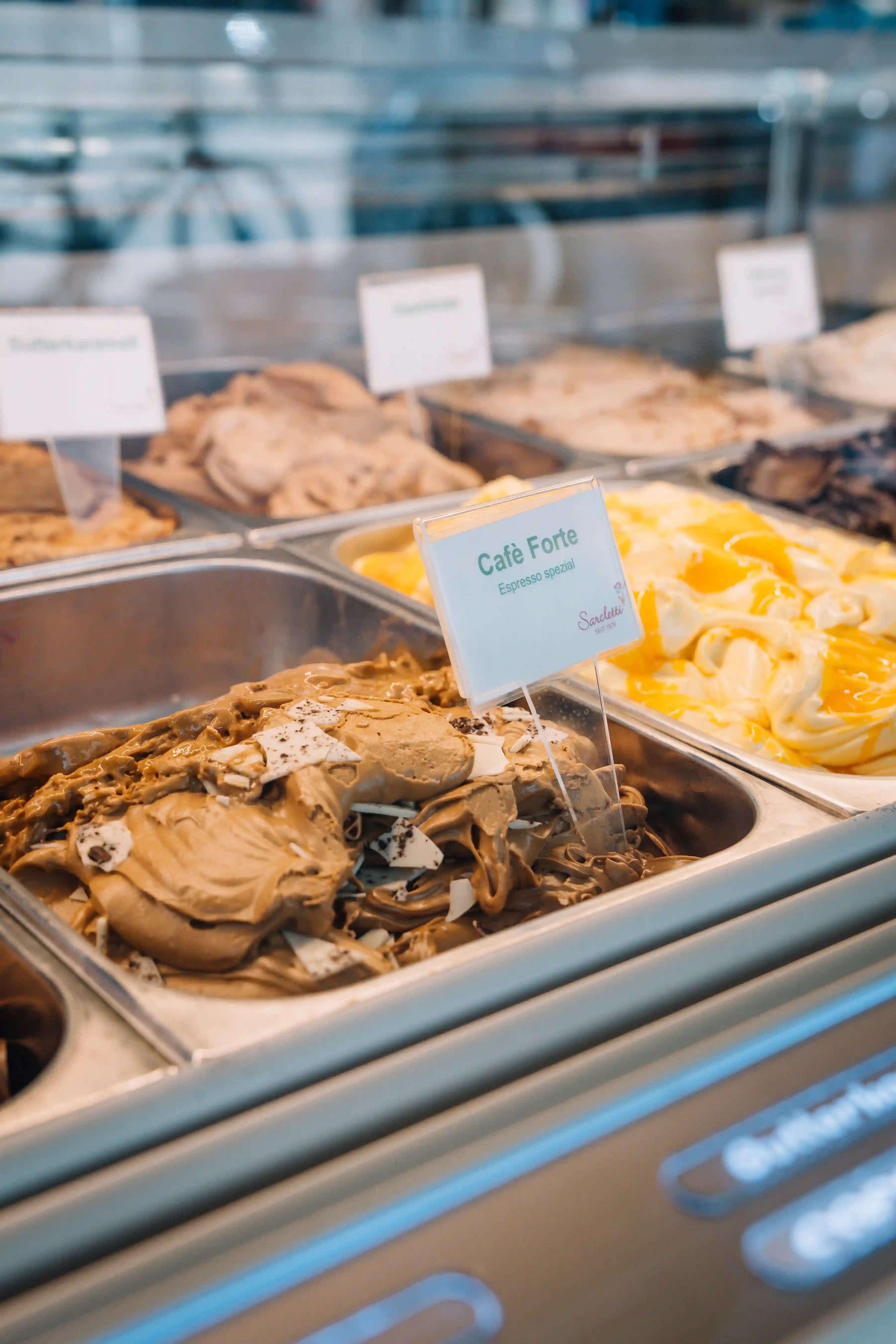 Close-up of creamy yellow and orange swirled gelato in a metal container.