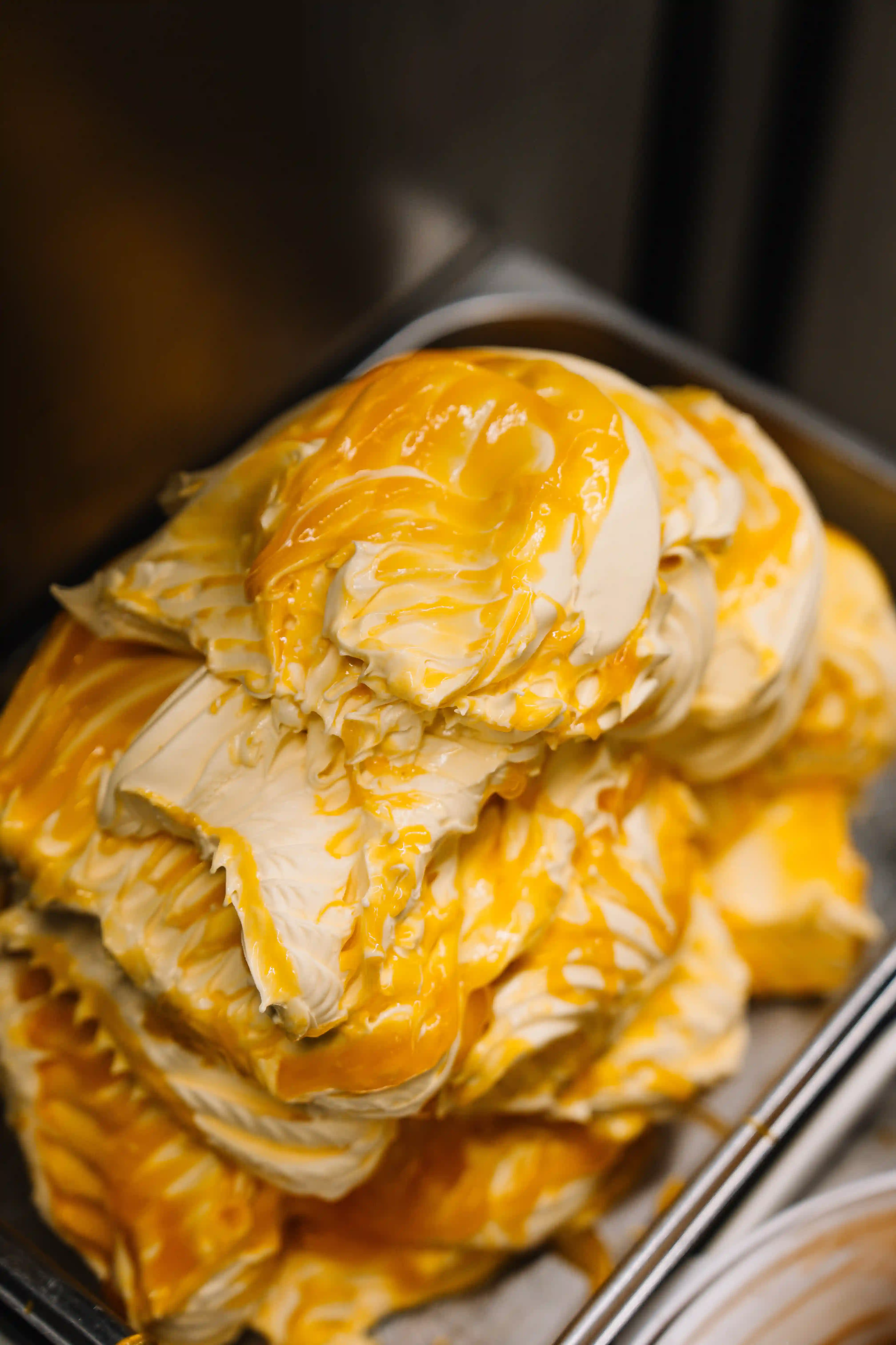 Creamy vanilla ice cream topped with thick orange sauce in a container.