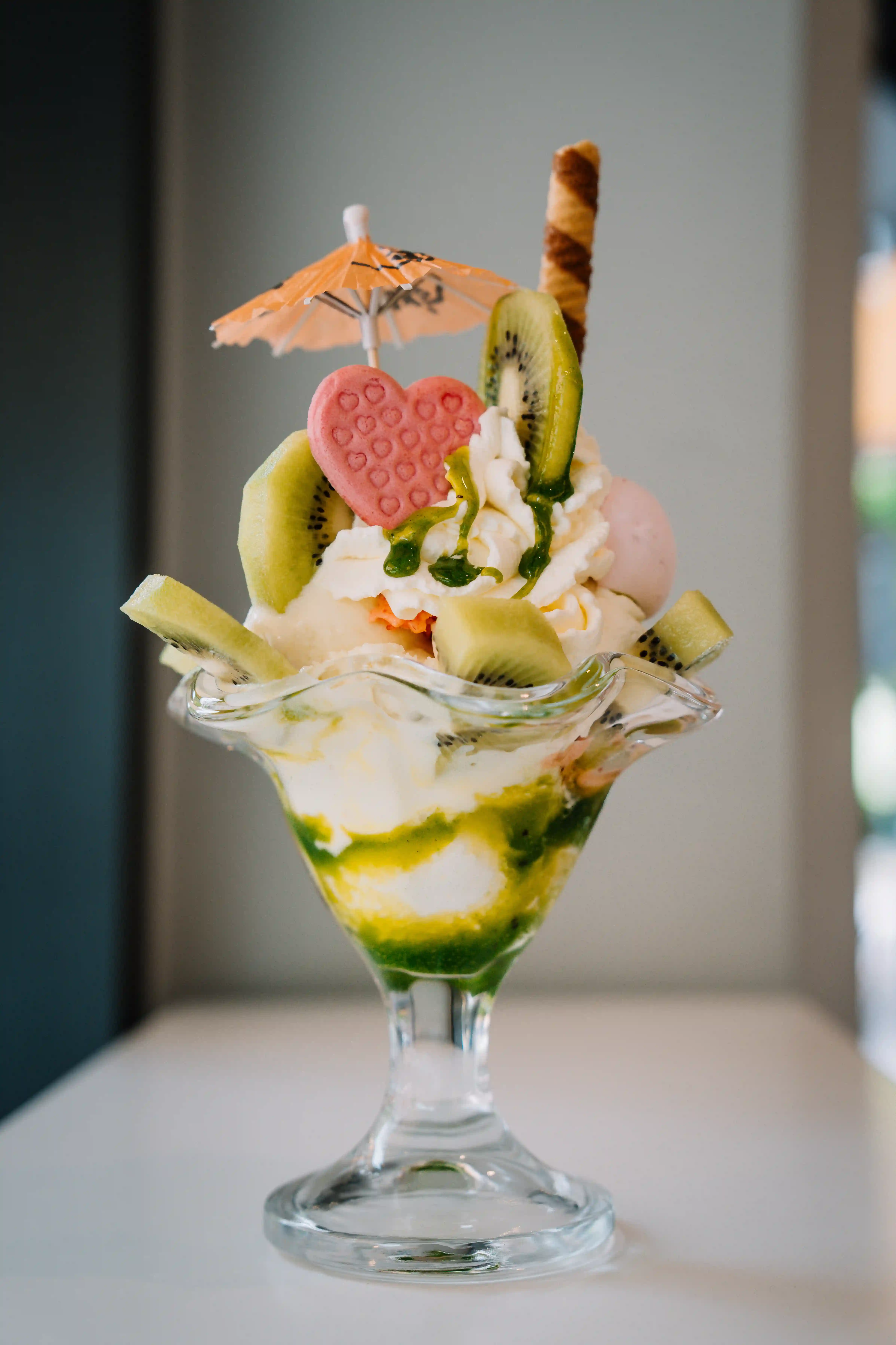 Eisbecher im Glas mit bunten Eiskugeln, Sahnehaube und Dekospieß