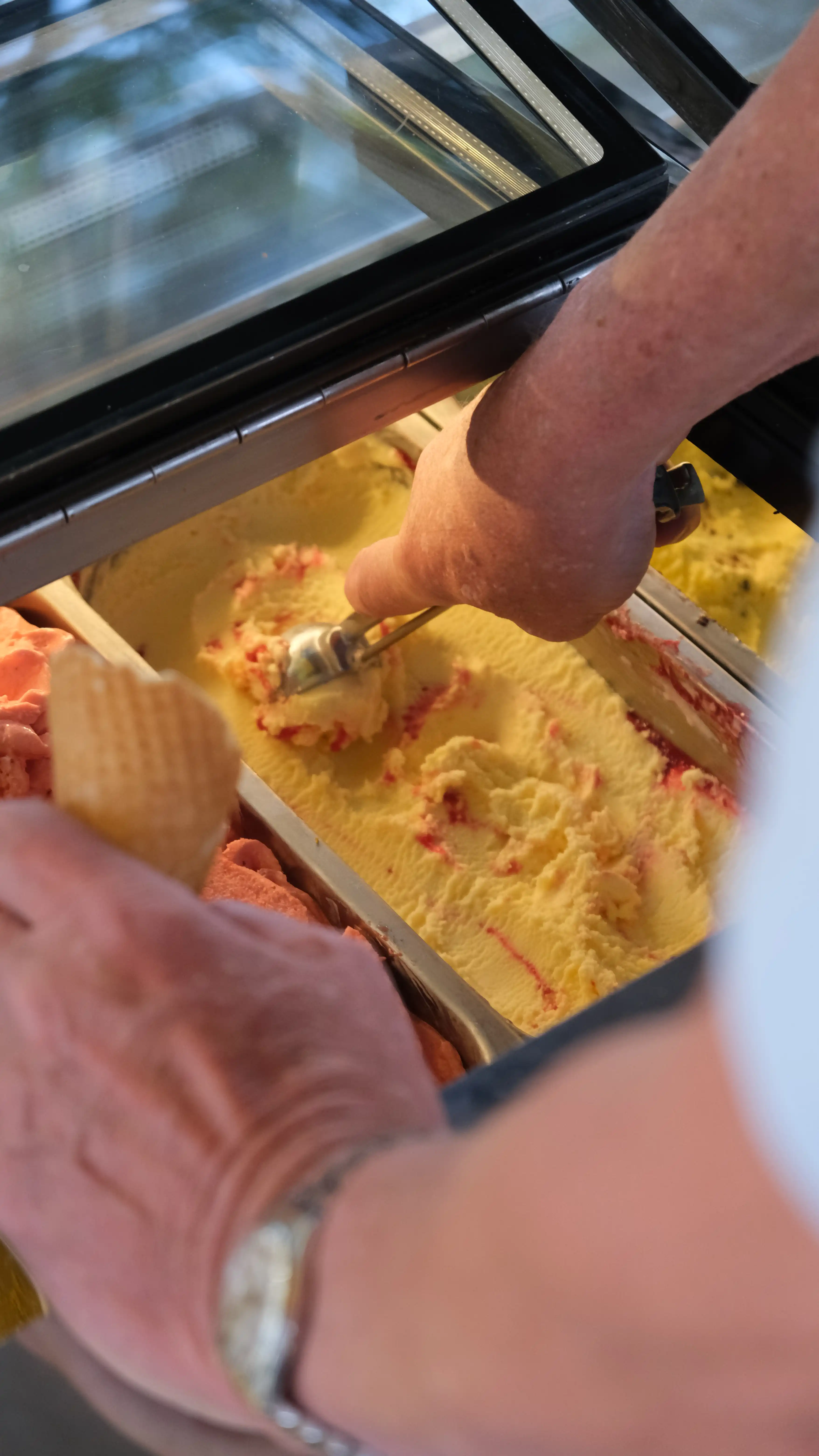 Nahaufnahme einer goldgelben Eiskugel beim Schöpfen am Sarcletti-Stand im Englischen Garten