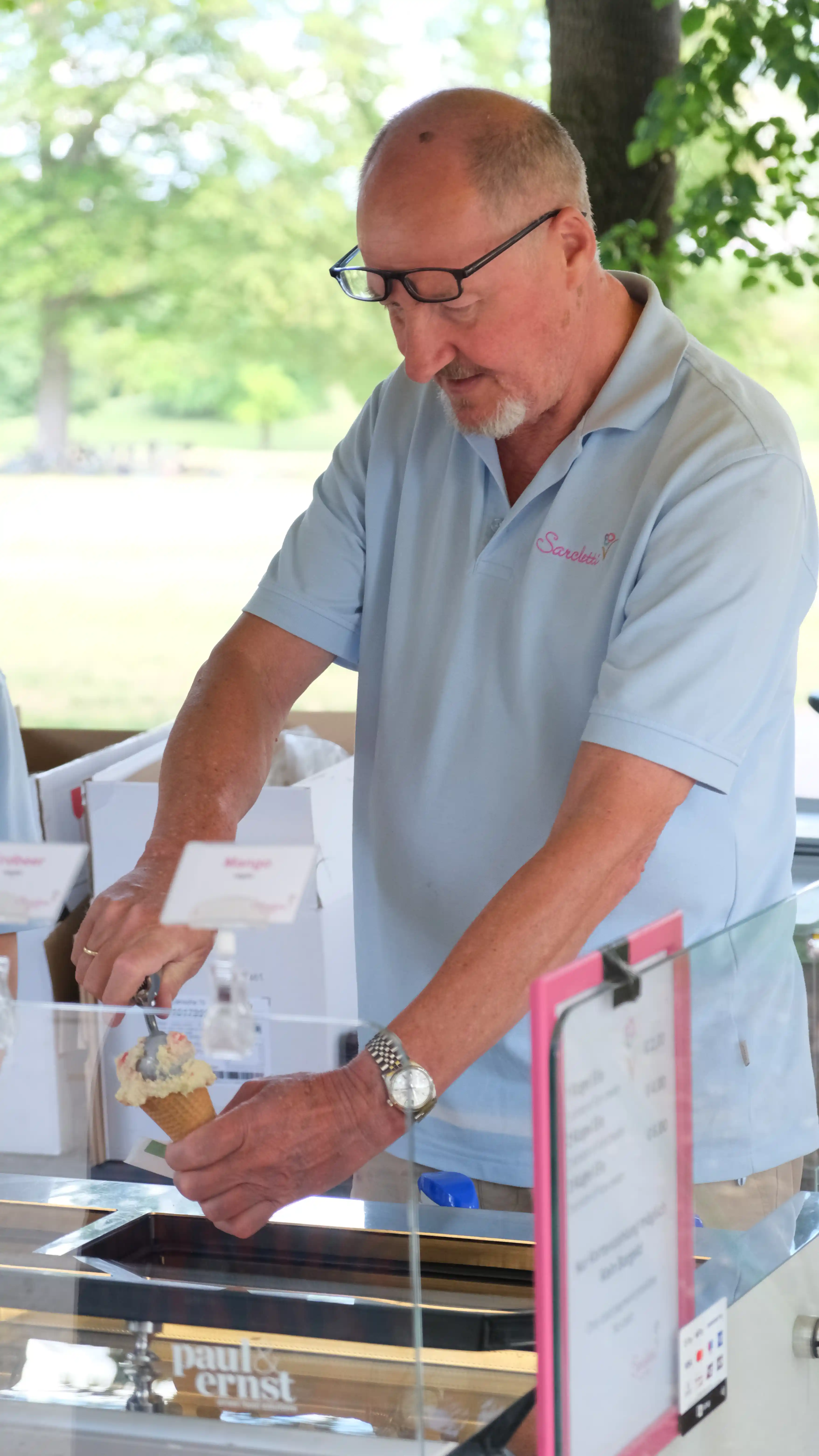 Sarcletti-Mitarbeiter schöpft Eis am Verkaufswagen im Englischen Garten München