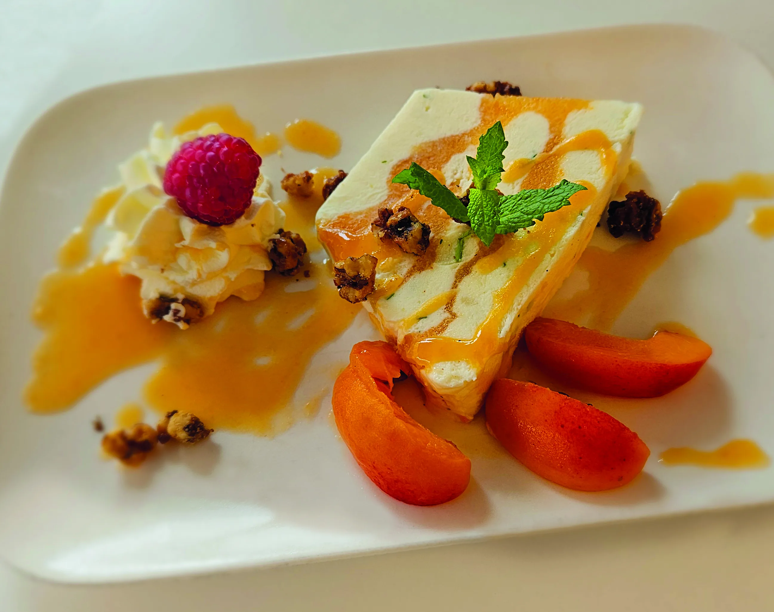 Weißer Teller mit Dessert, garniert mit Erdbeeren, Minze und Karamellsauce