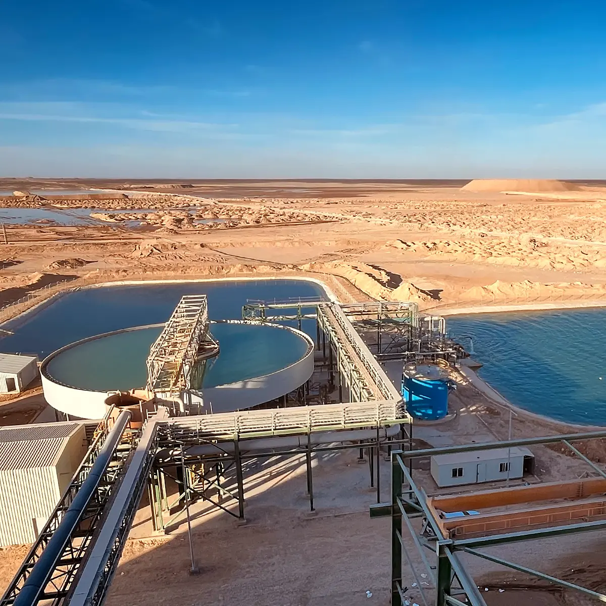Thickener and water process pond and surrounding desert landscape under a clear blue sky.