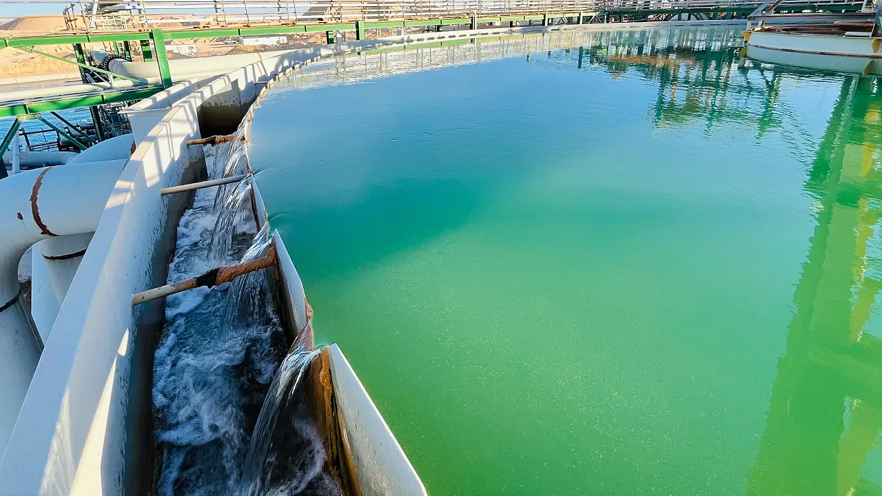 Water flowing through pipes into a large circular water treatment or storage tank.