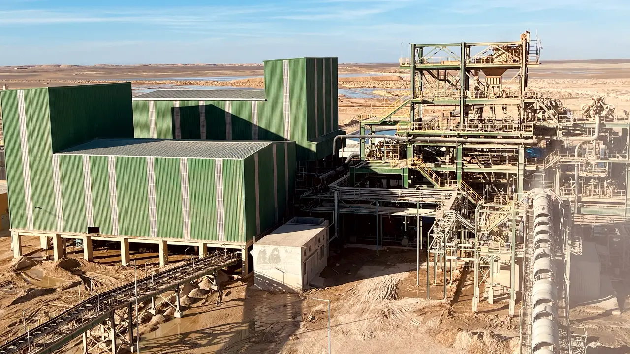 IDMI phosphate beneficiation plant in south Jordan, with green metal buildings and extensive pipework under clear sky in a desert landscape.