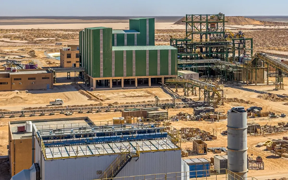 IDMI phosphate beneficiation plant with large green buildings and machinery in desert landscape.